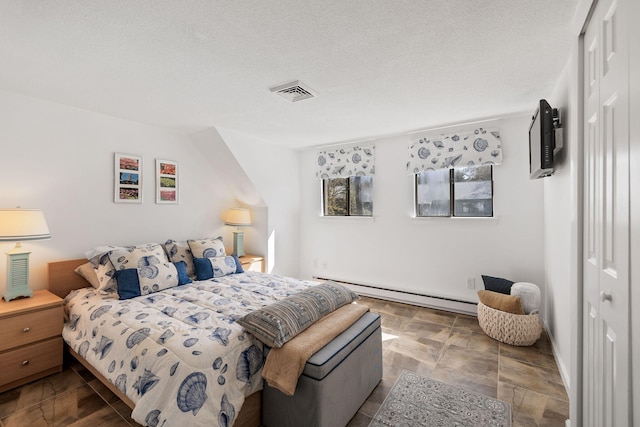 bedroom featuring visible vents, a textured ceiling, a baseboard heating unit, and a closet