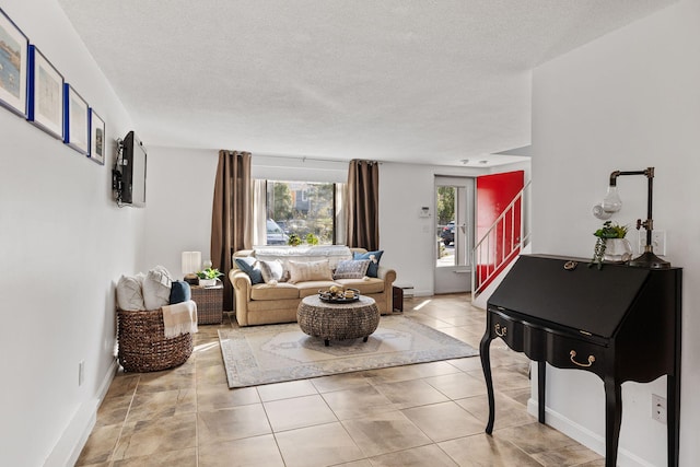 living area featuring light tile patterned floors, baseboards, stairway, and a textured ceiling