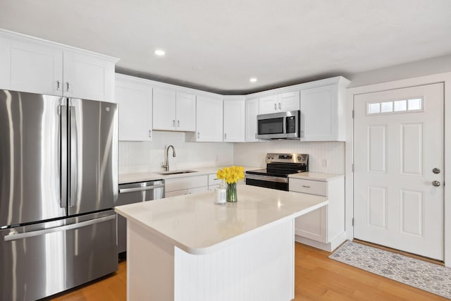 kitchen featuring a sink, white cabinets, light countertops, appliances with stainless steel finishes, and light wood finished floors