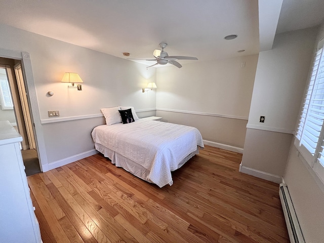 bedroom featuring ceiling fan, a baseboard radiator, and hardwood / wood-style flooring