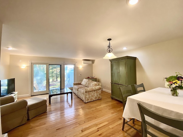 living room with a wall mounted air conditioner and light wood-type flooring