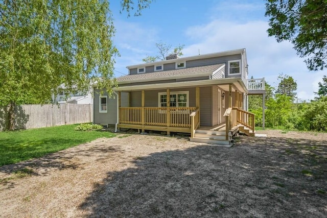 rear view of property featuring a chimney, fence, and a lawn