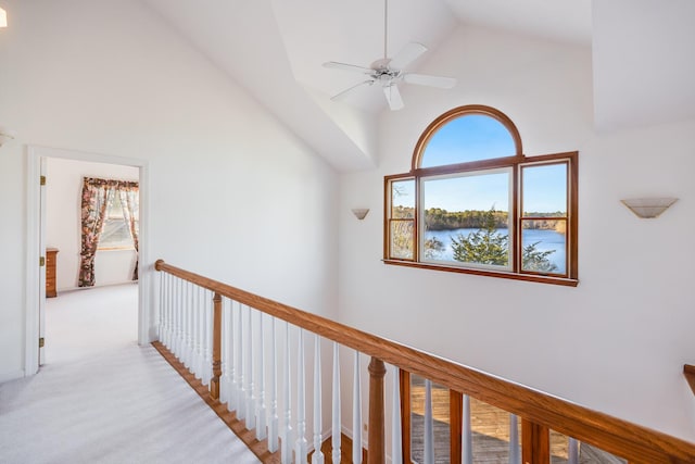 hall with an upstairs landing, carpet floors, high vaulted ceiling, and plenty of natural light