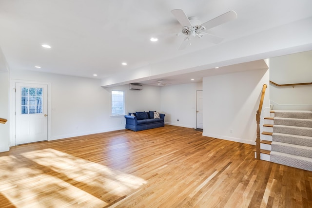 unfurnished room featuring a wall unit AC, a ceiling fan, and light wood-style floors
