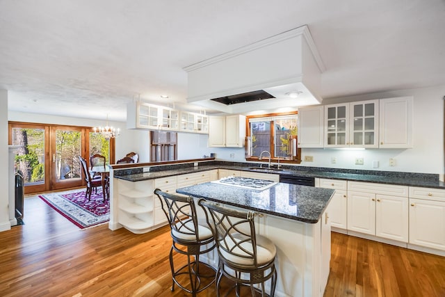 kitchen featuring a sink, a peninsula, white gas cooktop, open shelves, and a notable chandelier