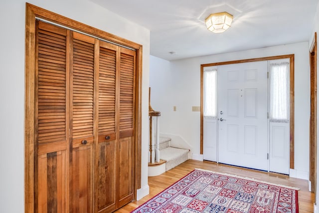 entrance foyer featuring light wood-style floors, stairway, and baseboards