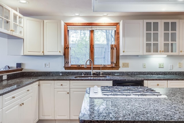 kitchen with white cabinets, white gas stovetop, a sink, and glass insert cabinets