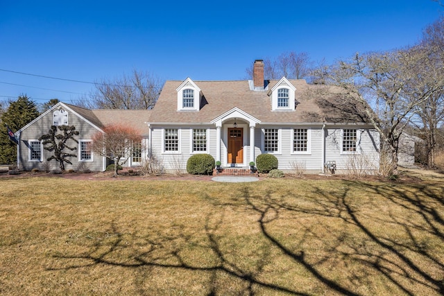 new england style home with a front yard, roof with shingles, and a chimney