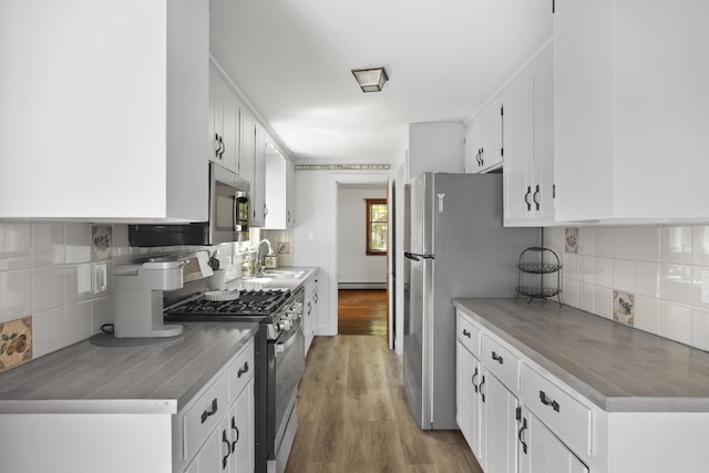 10 Devonshire Ln, South Dennis, MA 02660 - kitchen with stainless steel appliances, tasteful backsplash, white cabinetry, and light wood-type flooring