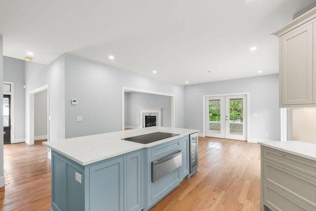 kitchen featuring beverage cooler, a kitchen island, a premium fireplace, french doors, and black electric cooktop