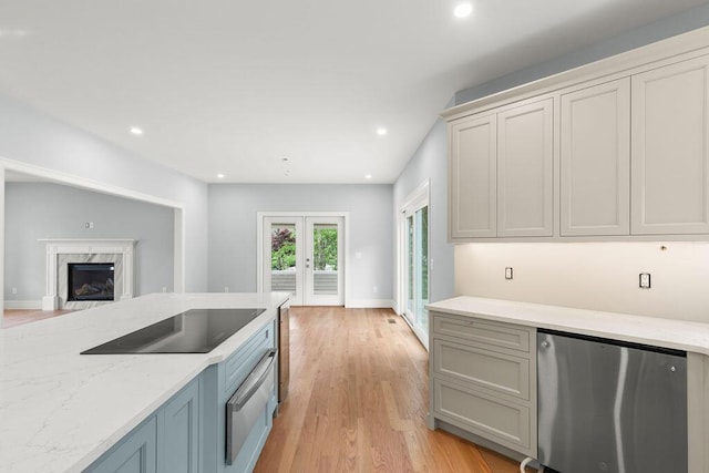 kitchen featuring light hardwood / wood-style floors, a fireplace, black electric stovetop, stainless steel refrigerator, and french doors