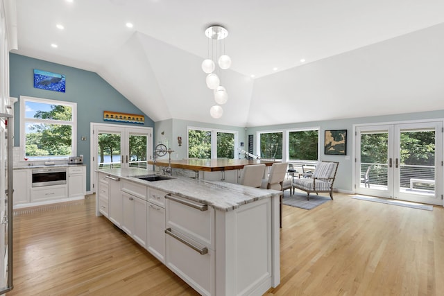 kitchen with french doors, a sink, light wood-style flooring, and white cabinets