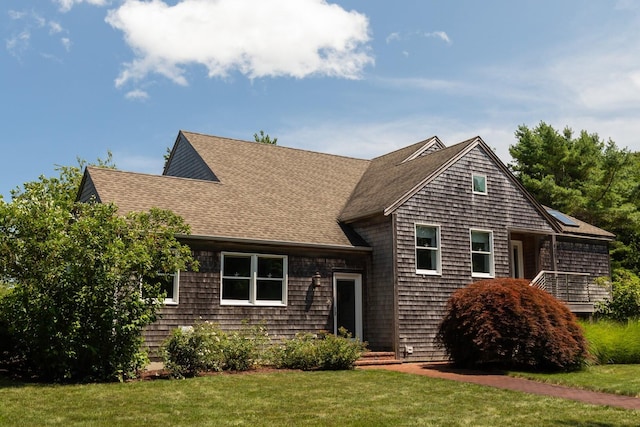 shingle-style home featuring roof with shingles and a front lawn