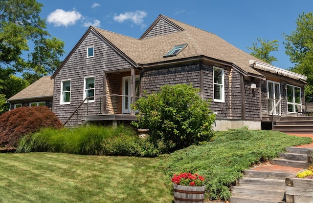 view of side of home with a lawn and roof with shingles