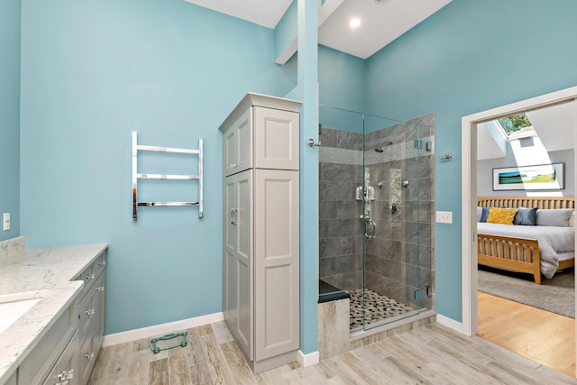 ensuite bathroom with a stall shower, vanity, baseboards, and wood finished floors