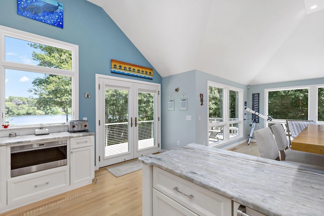 kitchen featuring white cabinetry, vaulted ceiling, french doors, light wood-type flooring, and plenty of natural light