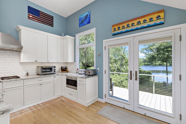 kitchen with a toaster, stainless steel gas cooktop, white cabinets, light stone countertops, and tasteful backsplash