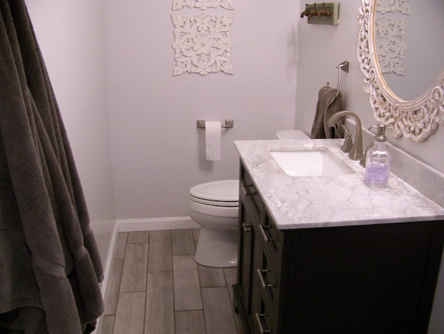 bathroom with toilet, vanity, baseboards, and wood tiled floor