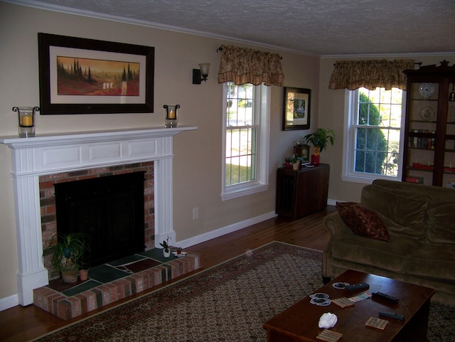 living area featuring wood finished floors, baseboards, a fireplace, a textured ceiling, and crown molding