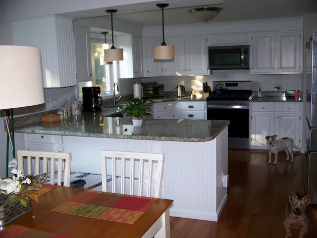 kitchen with dark wood-style floors, stone counters, a peninsula, white cabinets, and appliances with stainless steel finishes