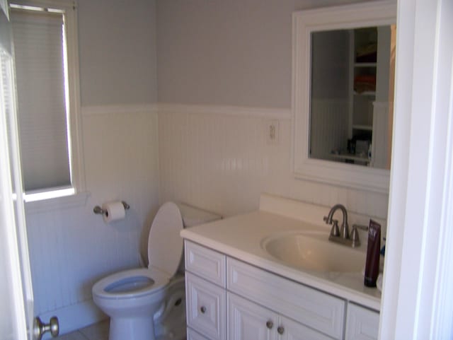 bathroom featuring wainscoting, toilet, and vanity