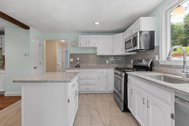 10 Briarfield Rd, South Dennis, MA 02660 - kitchen featuring stainless steel appliances, a kitchen island, white cabinetry, backsplash, and light stone counters