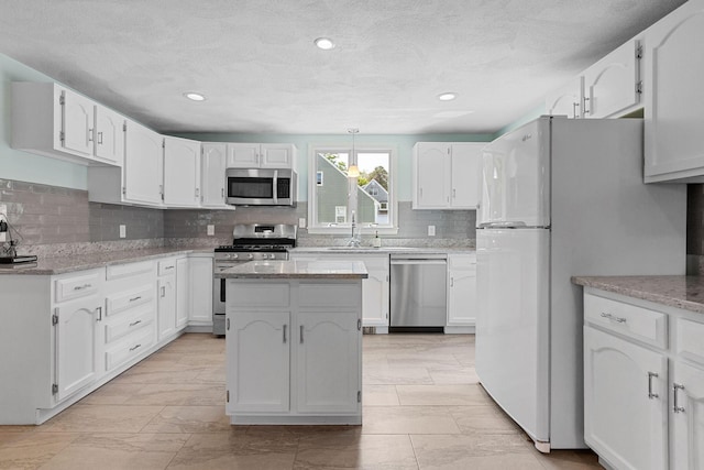 10 Briarfield Rd, South Dennis, MA 02660 - kitchen featuring stainless steel appliances, tasteful backsplash, white cabinetry, light stone countertops, and a kitchen island