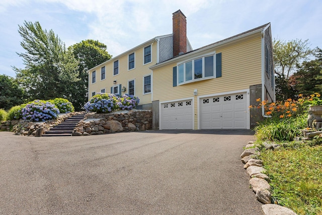 10 Briarfield Rd, South Dennis, MA 02660 - view of front of house featuring driveway, an attached garage, and a chimney