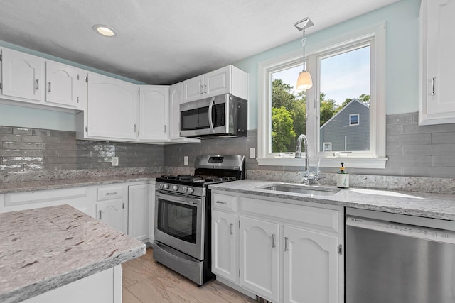 10 Briarfield Rd, South Dennis, MA 02660 - kitchen featuring stainless steel appliances, white cabinetry, light stone counters, hanging light fixtures, and tasteful backsplash