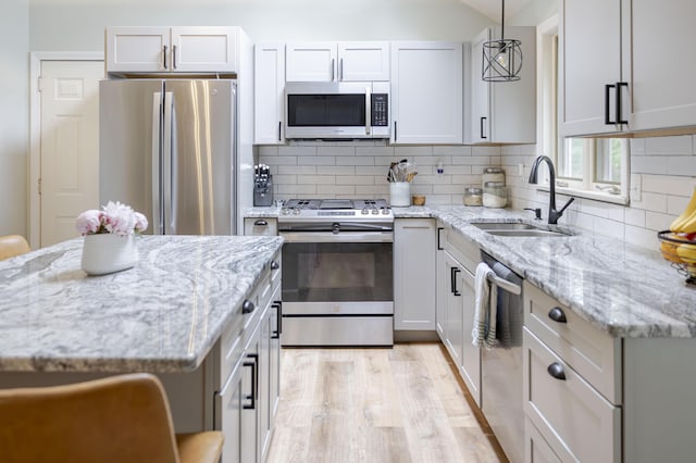 68 Harlow Rd, Sandwich, MA 02563 - kitchen featuring appliances with stainless steel finishes, backsplash, light wood finished floors, and light stone counters