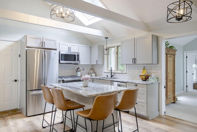 68 Harlow Rd, Sandwich, MA 02563 - kitchen featuring appliances with stainless steel finishes, vaulted ceiling, light stone countertops, tasteful backsplash, and a kitchen bar