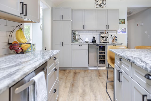68 Harlow Rd, Sandwich, MA 02563 - kitchen featuring beverage cooler, backsplash, light wood finished floors, stainless steel dishwasher, and light stone counters