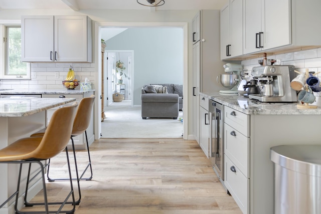 68 Harlow Rd, Sandwich, MA 02563 - kitchen featuring backsplash, light wood-style floors, light stone countertops, and wine cooler