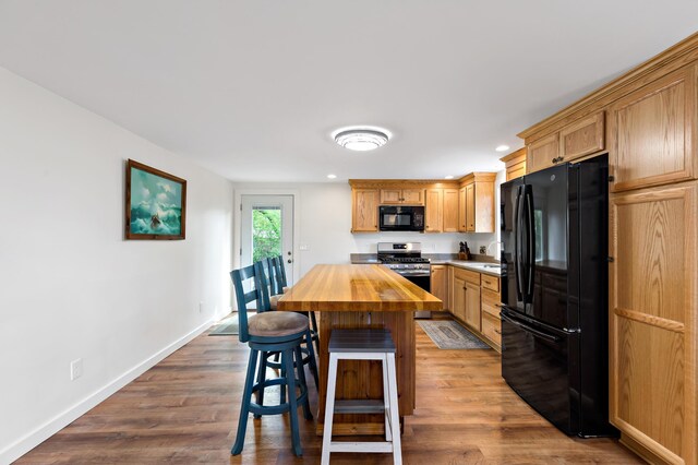 16 Town Neck Rd, Sandwich, MA 02563 - kitchen featuring a sink, a kitchen breakfast bar, butcher block countertops, baseboards, and black appliances