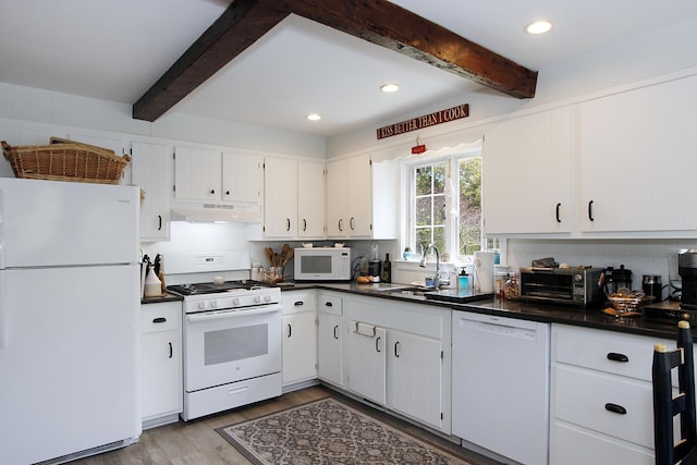 70 Deerfield Ln, Eastham, MA 02642 - kitchen with white appliances, under cabinet range hood, beam ceiling, dark countertops, and a sink