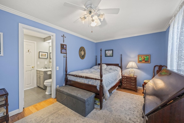 bedroom featuring light wood-type flooring, crown molding, and ensuite bathroom