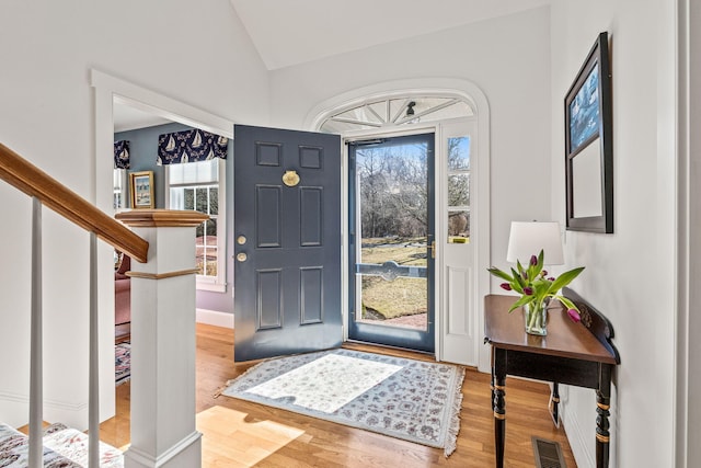 entryway featuring healthy amount of natural light, wood finished floors, stairway, and lofted ceiling