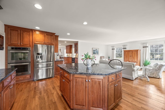 kitchen featuring appliances with stainless steel finishes, a center island, light hardwood / wood-style flooring, and dark stone counters