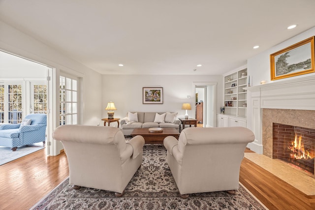 living room featuring hardwood / wood-style flooring, a high end fireplace, and built in features