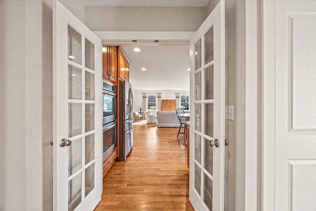 hall with french doors, light wood-type flooring, and recessed lighting