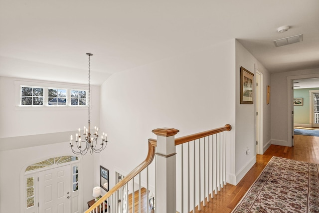 hall with lofted ceiling, hardwood / wood-style floors, and a notable chandelier