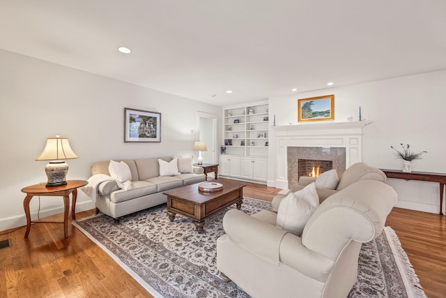 living room featuring hardwood / wood-style floors, built in shelves, and a fireplace