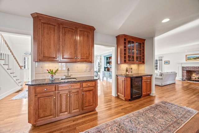 kitchen with wine cooler, sink, a brick fireplace, and dark stone countertops