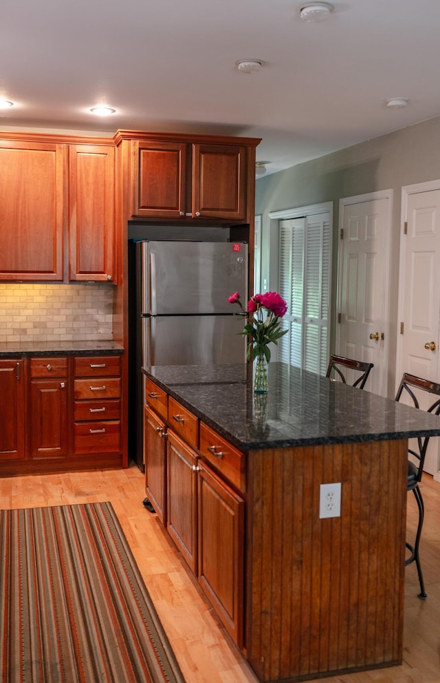 208 Irenes Way, Tisbury, MA 02568 - kitchen featuring a kitchen bar, light wood finished floors, decorative backsplash, dark stone counters, and freestanding refrigerator