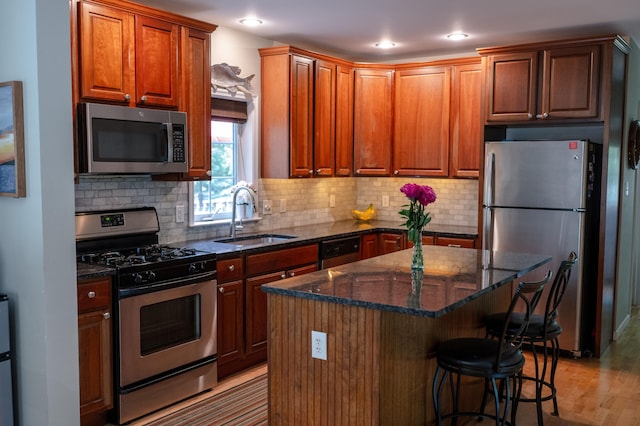 208 Irenes Way, Tisbury, MA 02568 - kitchen with appliances with stainless steel finishes, dark stone counters, a kitchen island, decorative backsplash, and a breakfast bar
