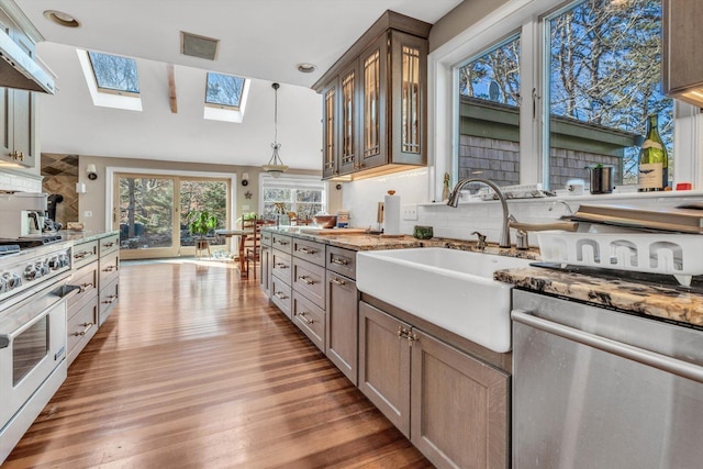13 Try Works Rd, Truro, MA 02666 - kitchen with stainless steel appliances, backsplash, a skylight, light wood-type flooring, and glass insert cabinets