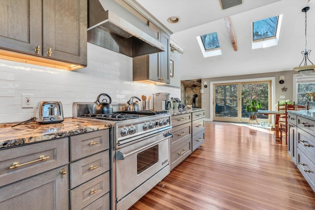 13 Try Works Rd, Truro, MA 02666 - kitchen with stainless steel stove, wall chimney exhaust hood, gray cabinetry, a skylight, and vaulted ceiling