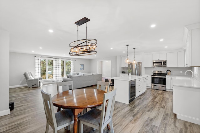 dining area with sink, light wood-type flooring, and wine cooler