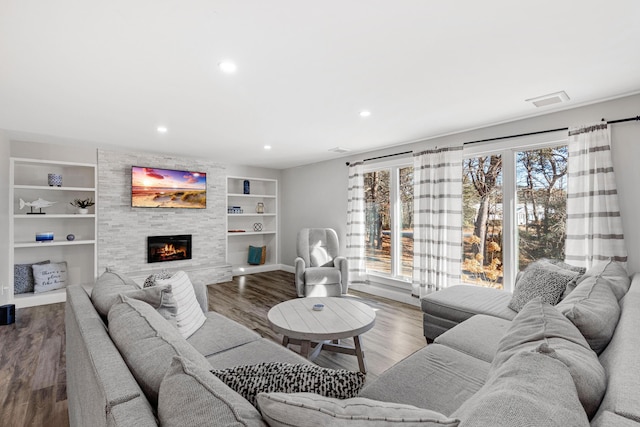 living room featuring hardwood / wood-style floors, built in features, and a fireplace