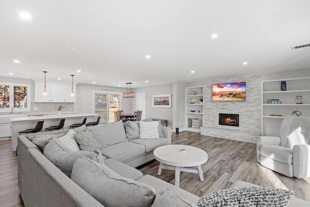 living room with a fireplace, built in shelves, light hardwood / wood-style flooring, and a healthy amount of sunlight